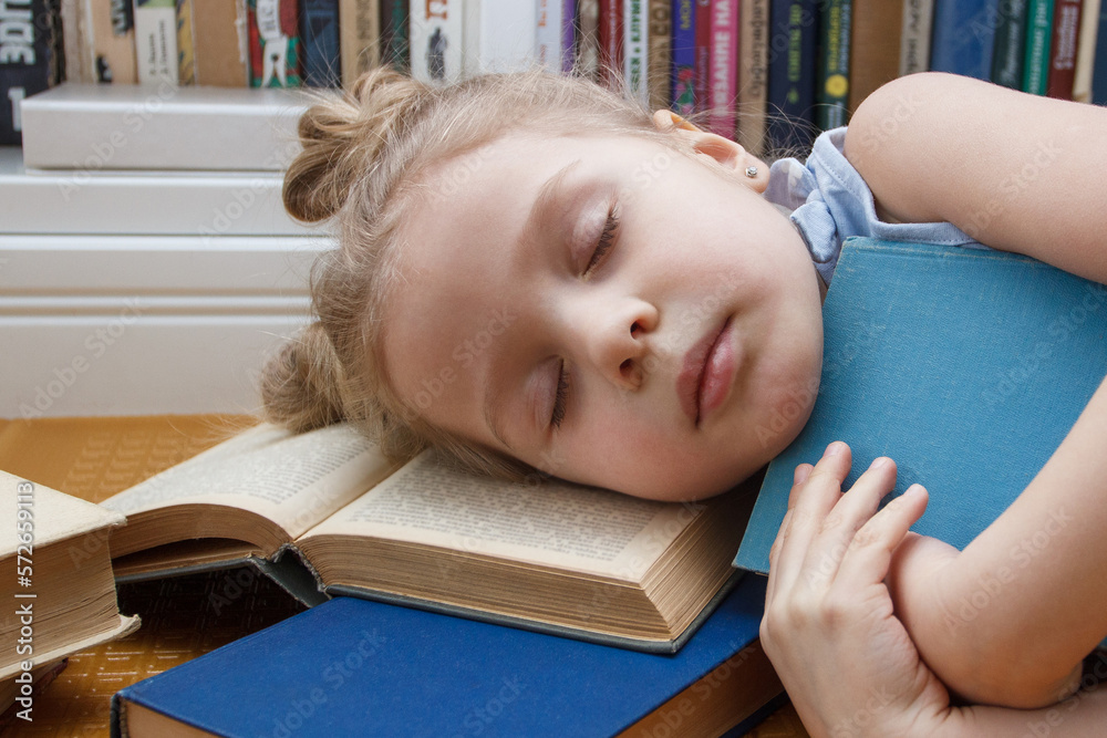 Little cute girl sleeping with books in the front of bookshelf. Concept of education Little cute girl sleeping with books in the front of bookshelf. Concept of education