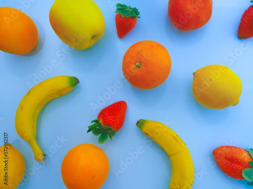 Fototapeta Naklejka Na Ścianę i Meble -  Colorful fresh and healthy fruit over a blue background. Orange, strawberry, mandarin, tangerine, banana, orange, apple, lemon. flat lay design, top view. 