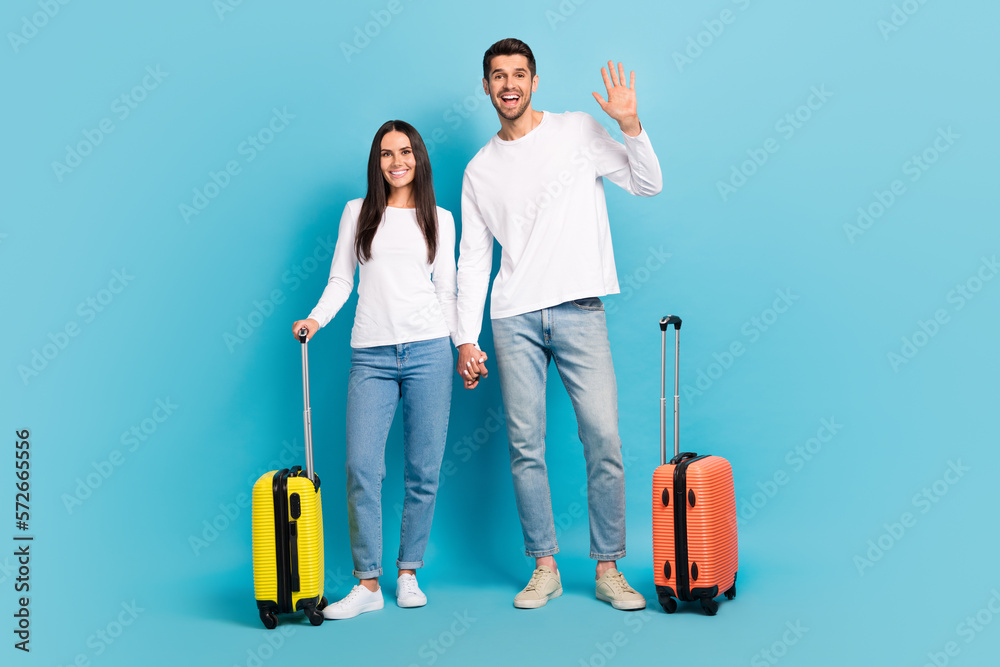 Full length photo of two excited positive people hold arms waving hi isolated on blue color background Full length photo of two excited positive people hold arms waving hi isolated on blue color background