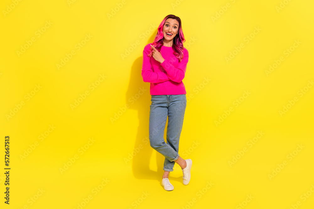 Full length photo of adorable impressed girl dressed vibrant pullover pointing empty space isolated yellow color background Full length photo of adorable impressed girl dressed vibrant pullover pointing empty space isolated yellow color background