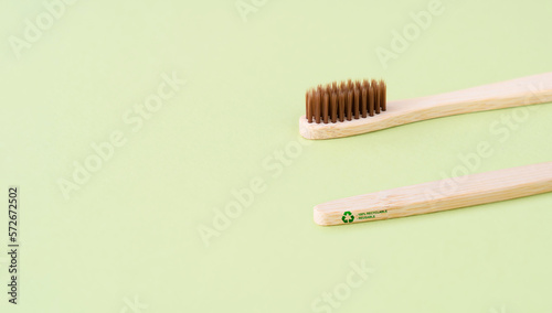 Wooden eco-friendly toothbrush on a green background. Recycling sign on a toothbrush. Zero waste concept