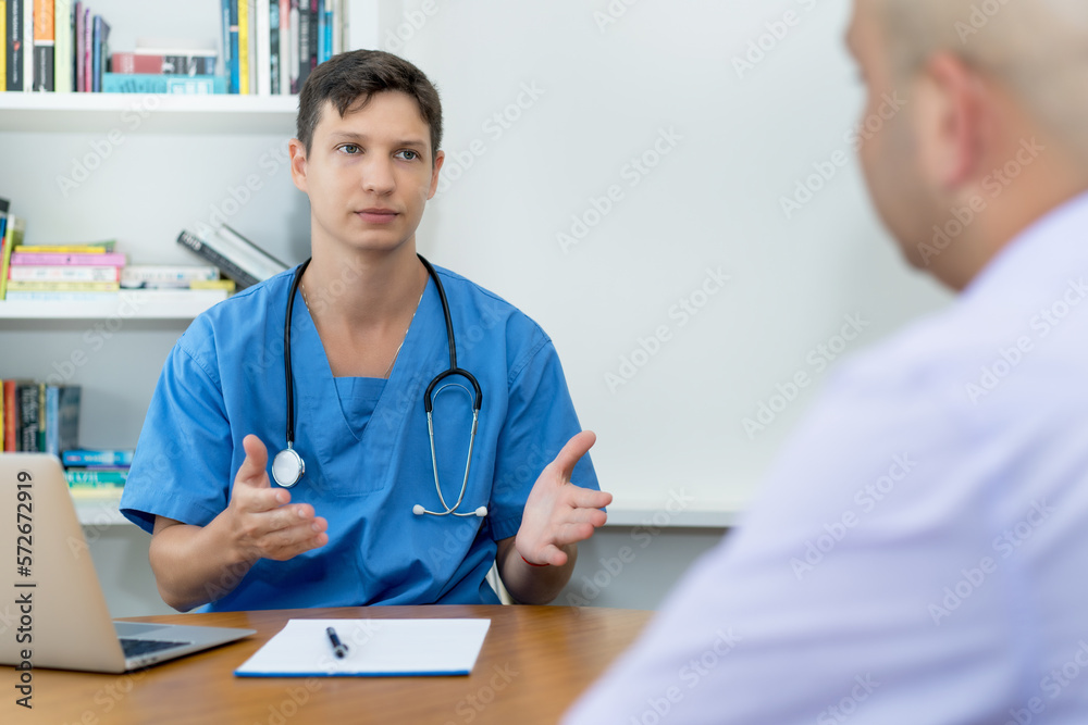 Handsome young male doctor or nurse talking with patient about pain and health Handsome young male doctor or nurse talking with patient about pain and health