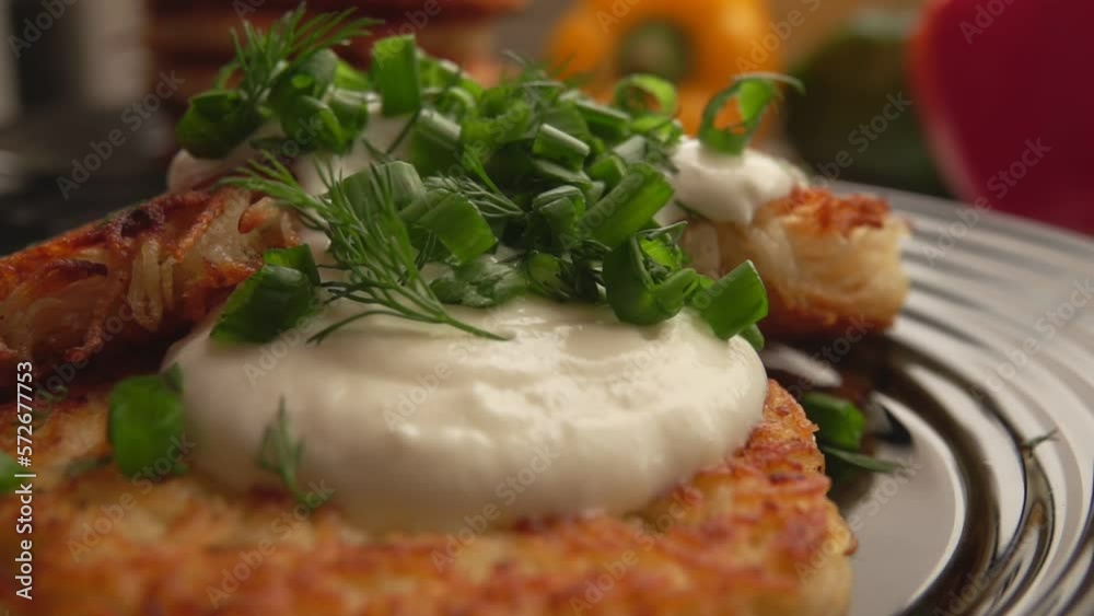 Sliced green onions and dill fall on a potato pancake with yogurt Sliced green onions and dill fall on a potato pancake with yogurt