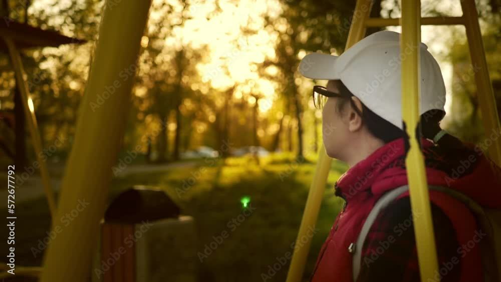 Slow motion unrecognizable adult woman in a white baseball cap outdoors at sunset,lens flare
