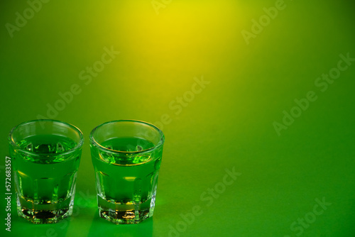 Shot glasses lined up against emerald green theme background waiting to be filled and slammed in celebrations for St Patrick's day. Irish holiday is popular drinking event when people party
