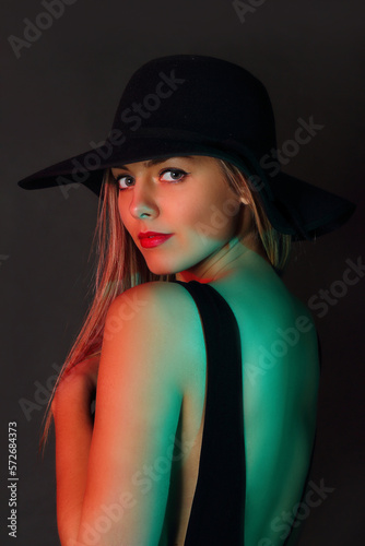 Young woman with hat in studio posing on black background