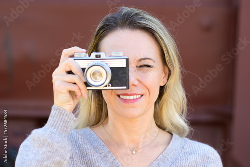 Smiling woman with an old camera taking a picture