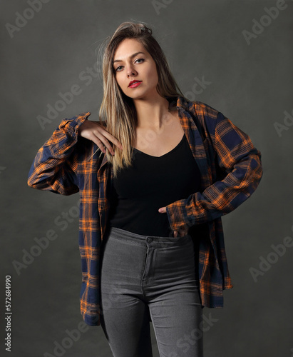 Woman in studio, in colorful shirt posing on gray background