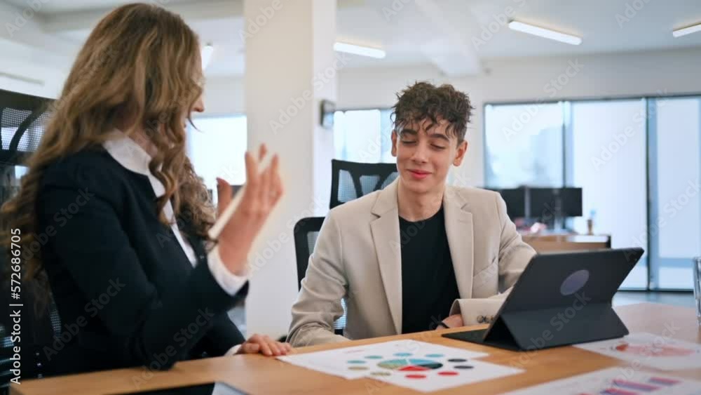 Business session in an office. Woman and a young man discussing business affairs. Gadgets with graphs and notes. Slow motion Business session in an office. Woman and a young man discussing business affairs. Gadgets with graphs and notes. Slow motion