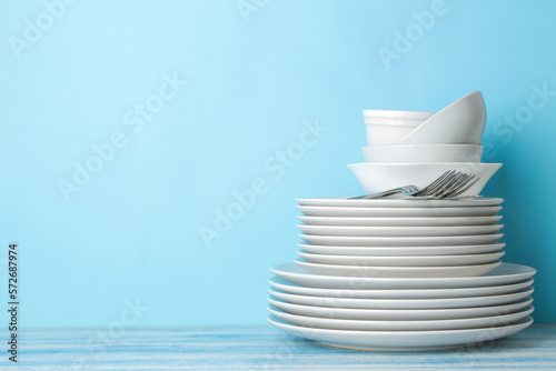 many different utensils. Tableware on a blue background. Clean tableware. various plates, bowls and cups.
