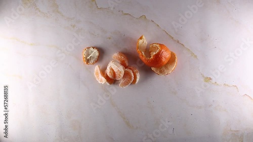 Womans hands peeling a clementine orange, top view on marble table