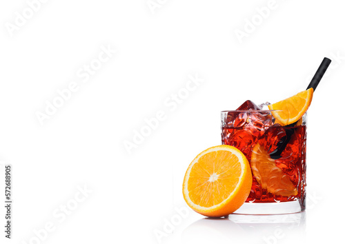Negroni Cocktail in crystal glass with ice cubes and orange slices with straw and half of fresh orange on white background with reflection with reflection.