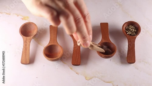 Different spices in wooden spoons process of putting by woman hand
