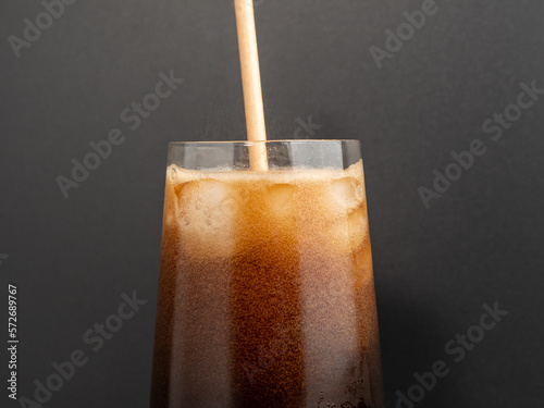 Glass of cola with ice on a black background. Close-up.