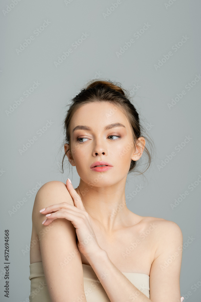 young woman with bare shoulders and natural makeup posing isolated on grey. young woman with bare shoulders and natural makeup posing isolated on grey.