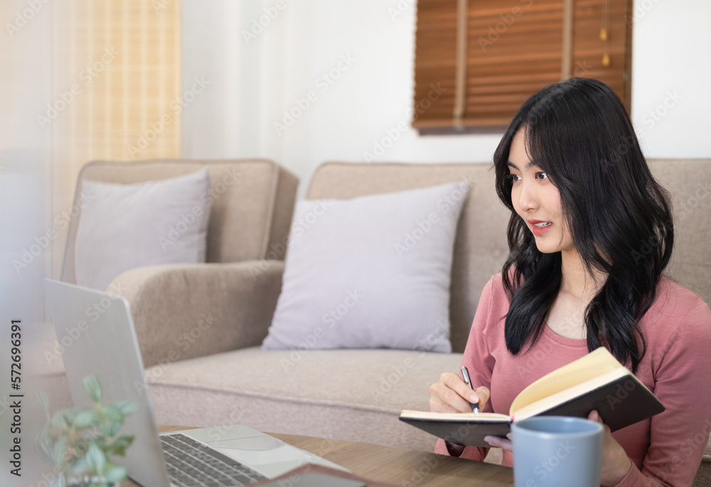 Woman on remote work or online education, using laptop computer, making notes, indoors at home at daytime. Online business, young professional at workplace. Working from home. Woman on remote work or online education, using laptop computer, making notes, indoors at home at daytime. Online business, young professional at workplace. Working from home.