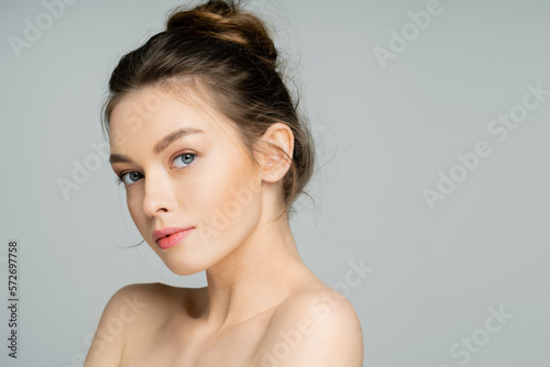 Young woman with natural makeup looking at camera isolated on grey.