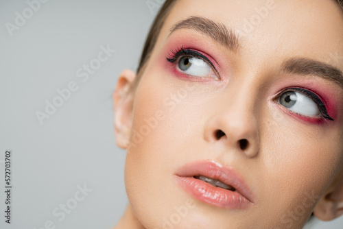 close up portrait of pretty woman with perfect skin and makeup looking away isolated on grey.