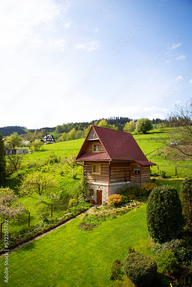 Old wooden cottage in a valley on a hill, beautiful blue sky. Landscaping. View from the window.