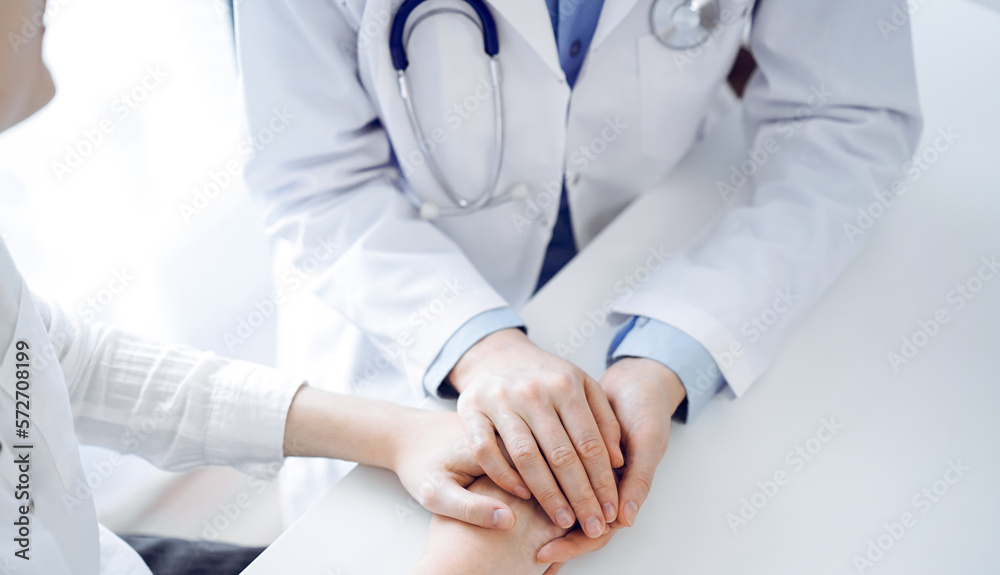 Doctor and patient sitting near each other at the table in clinic office. The focus is on female physician's hands reassuring woman, only hands, close up. Medicine concept Doctor and patient sitting near each other at the table in clinic office. The focus is on female physician's hands reassuring woman, only hands, close up. Medicine concept