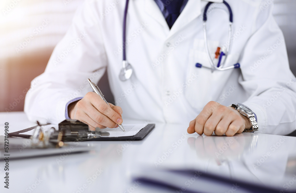 unknown-male-doctor-sitting-and-working-with-clipboard-of-medication