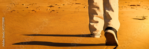 Man walking on the sand at sunset, seen from behind, photo