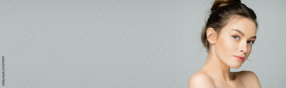Fototapeta premium Young fair haired woman with naked shoulders looking at camera isolated on grey, banner.
