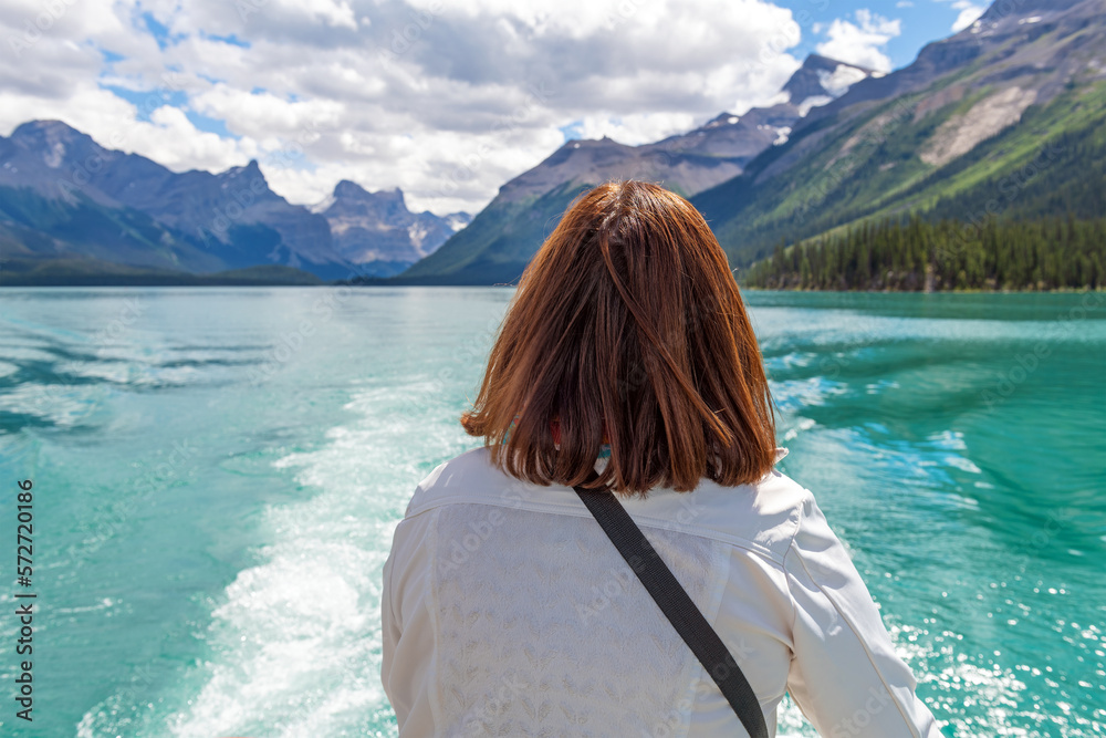 Female tourist enjoying the view over Maligne Lake during boat excursion, Jasper national park, Canada.