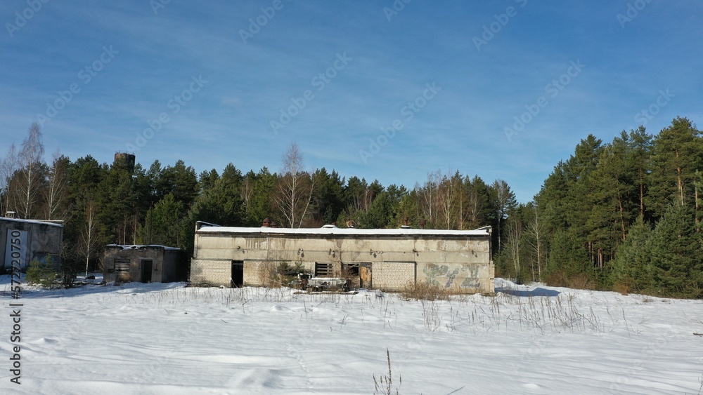 Ruins of an old farm. The buildings of the former Soviet collective farm in the middle of the forest under the snow in the cold. Abandoned buildings of the agricultural state farm of the USSR.