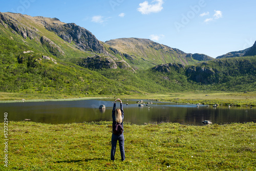 Young woman enjoy the beautiful natural scenery in the north. Lake and mountains. Tourist attraction in Norway. Amazing scenic outdoor view. Travel, adventure, relaxed lifestyle. Lofoten Islands