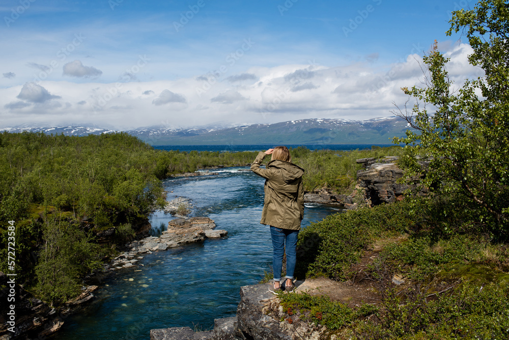 A young woman is enjoying the beautiful natural scenery in the north. Canyon and mountain river. Tourist attraction in Finland. Amazing scenic outdoor view. Travel, adventure, relaxed lifestyle