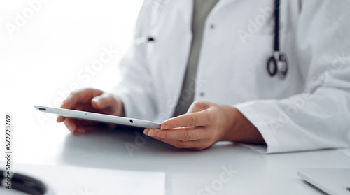 Unknown doctor woman sitting and writing notes at the desk in clinic or hospital office  close up. Medicine concept