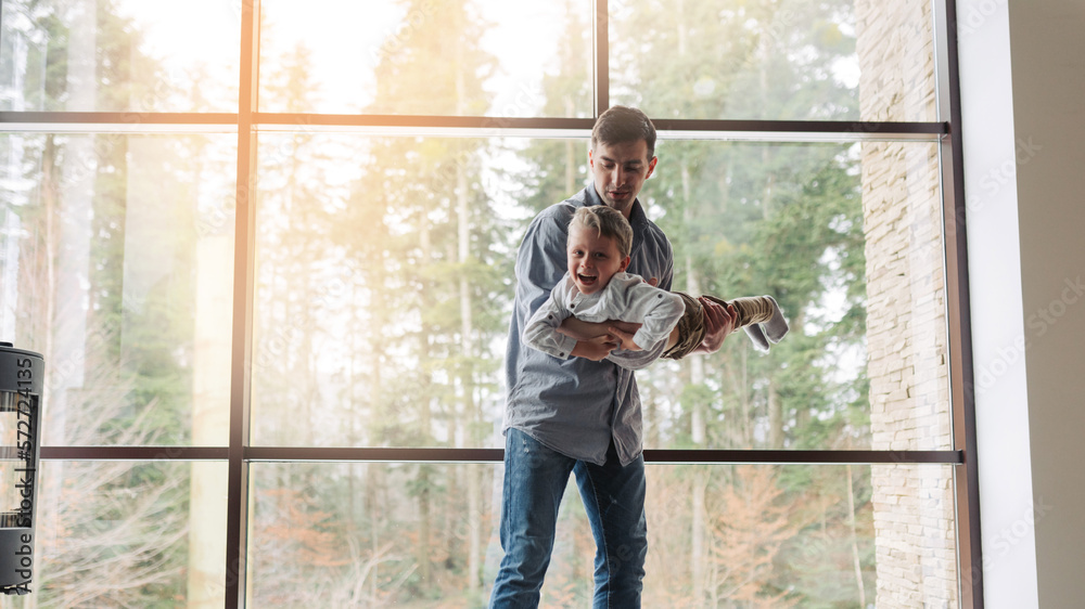 Father and son are smiling while spending time together. Father playing with his son at home. Father`s day concept Father and son are smiling while spending time together. Father playing with his son at home. Father`s day concept