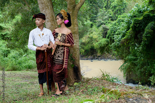 balinese couple walking in tropic forest wearing kebaya or traditional costume photo
