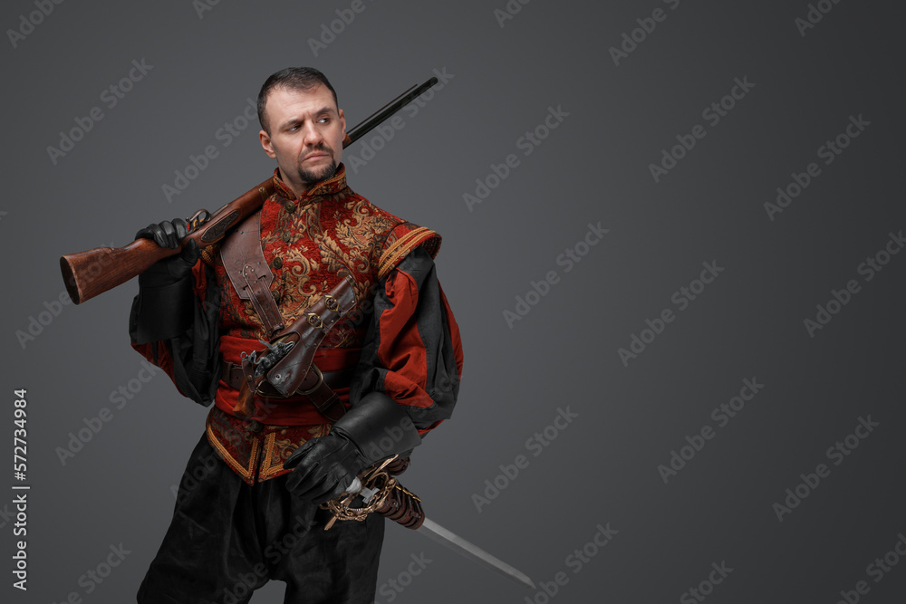 Shot of medieval musketeer man dressed in antique stylish suit holding rifle. Shot of medieval musketeer man dressed in antique stylish suit holding rifle.
