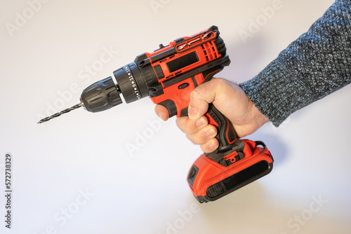 Men's hand holding an electric drill with batteries without cables on a white background.