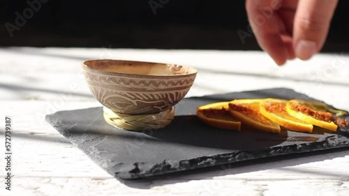 hand placing mezcal shot in traditional bowl and taking orange slice