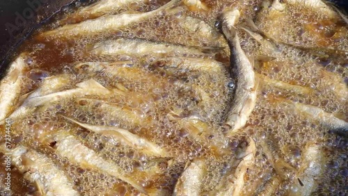 Fish fried in oil - deep frying small sprats or common bleak in hot boiling and bubbling fat. photo