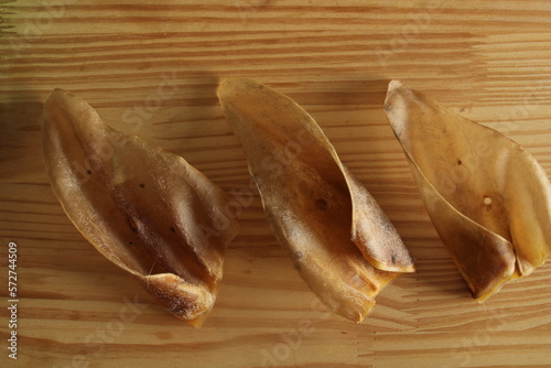 Photography Dehydrated ox ear in a wooden background. Dog treats.