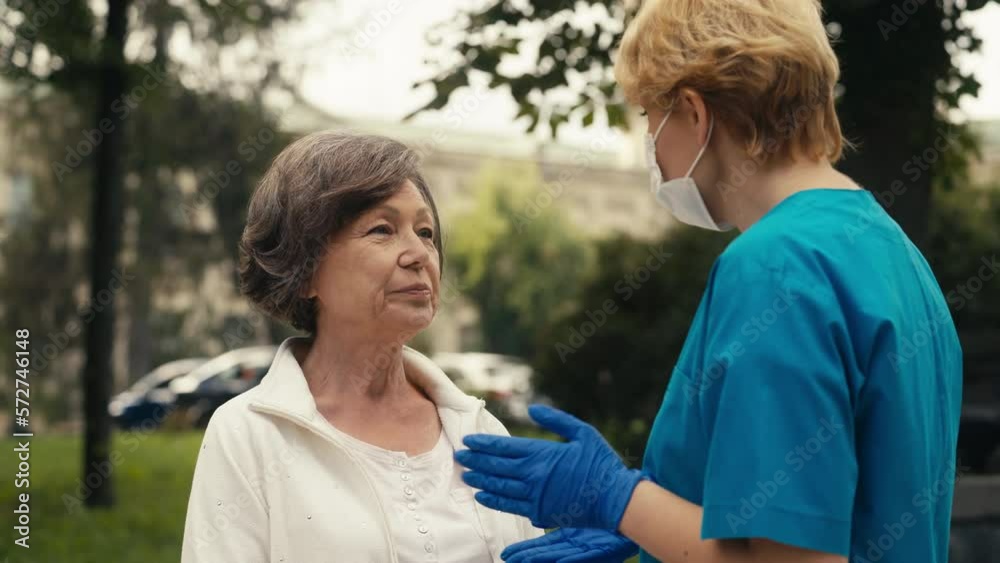 Female nurse in medical mask talking with senior patient outdoor, healthcare Female nurse in medical mask talking with senior patient outdoor, healthcare