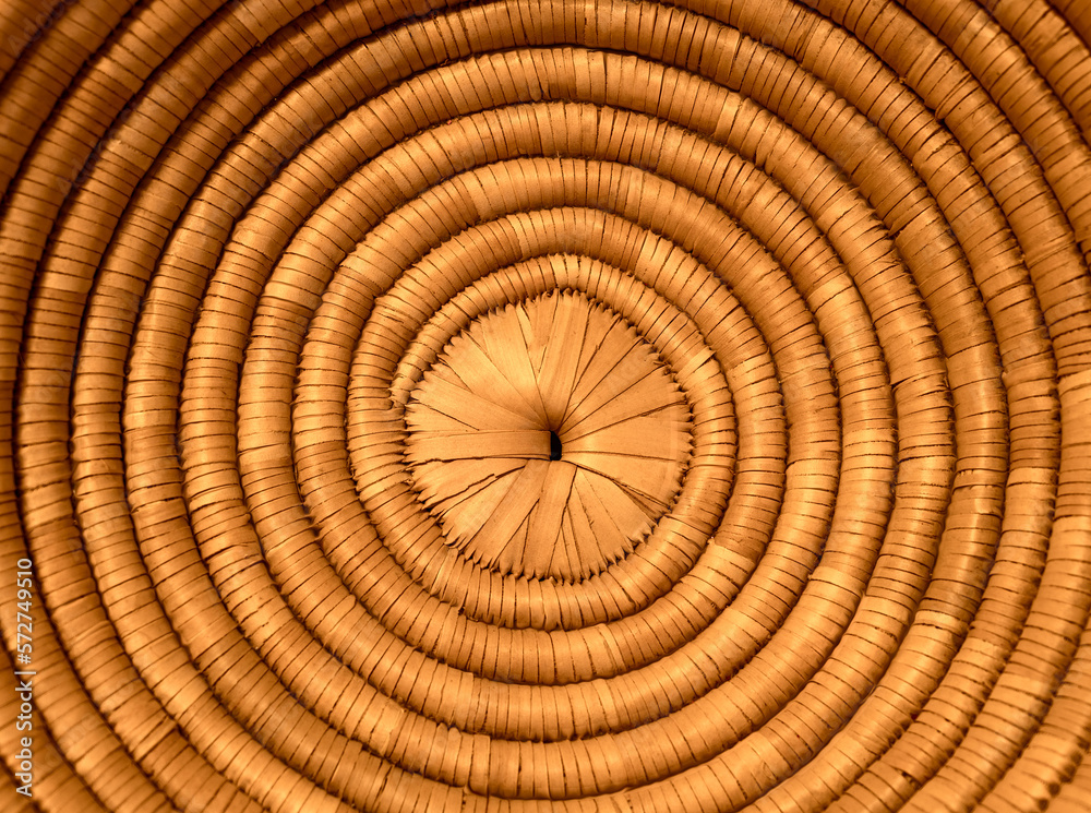 Fototapeta premium background with concentric circles of wicker around a small hole in the middle lit by a warm light