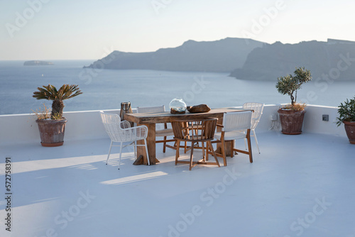 Amazing view from luxury white terrace with wooden table on Santorini island. Greek resort Thira, Greece, Europe. Traveling concept background. Summer vacation