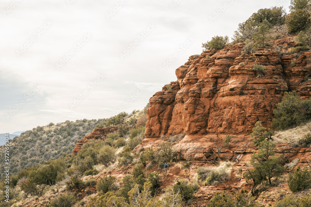 Fototapeta premium Young female woman walking on popular hiking trail in Sedona Arizona during the day on the famous Airport mesa loop hike near Vortex in Oak Creek area