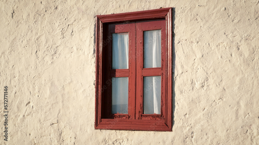 Ventana con marco de madera rojo y cortina en pared de estuco blanco de casa rural Ventana con marco de madera rojo y cortina en pared de estuco blanco de casa rural