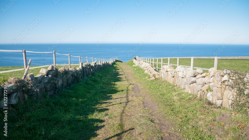 Camino entre praderas de hierba valladas junto al mar en Asturias Camino entre praderas de hierba valladas junto al mar en Asturias
