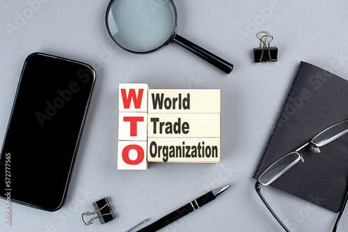 wooden cubes WTO - World Trade Organization wtih notebook , magnifier and smartphone, business concept photo