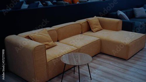 A variety of sofas in many colors. In the center, a yellow-brown sofa with decorative pillows next to a small wooden table. Black background. 4k video.