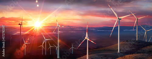 Wind Turbines At Sunset In Rural Mountain Landscape With Light Flare Effect