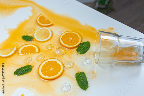 Overturned glass with orange juice on the table