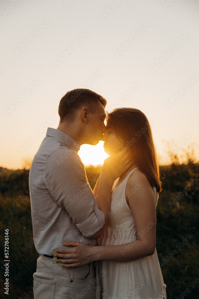 Man hug a woman and kiss.Silhouette of a couple in love and a tree in the field. Lovestory in summer at sunset Man hug a woman and kiss.Silhouette of a couple in love and a tree in the field. Lovestory in summer at sunset